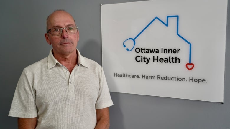 a man standing beside a sign