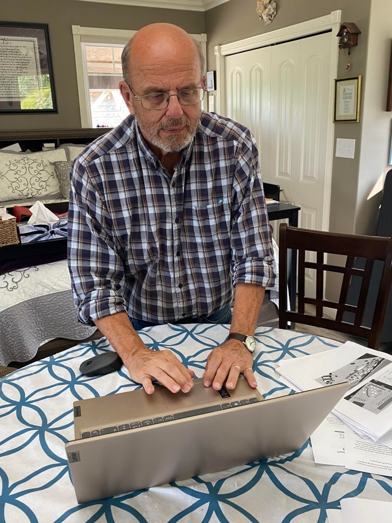 Man types on laptop at kitchen table