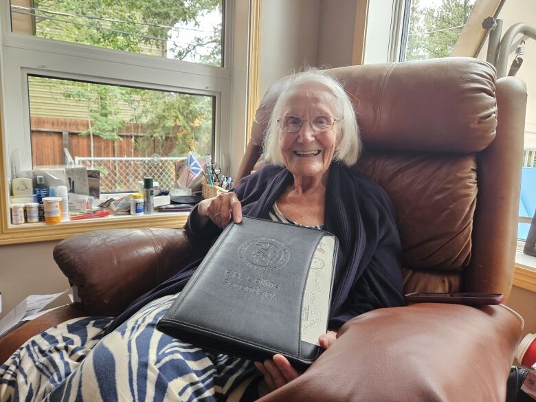 Person sitting on a couch, holding a leather folder that says F. H. Collins on it. 