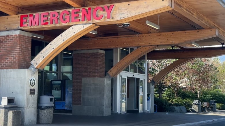 A vending machine sits outside an entranceway that has the words Emergency Room above it on a wood frame.