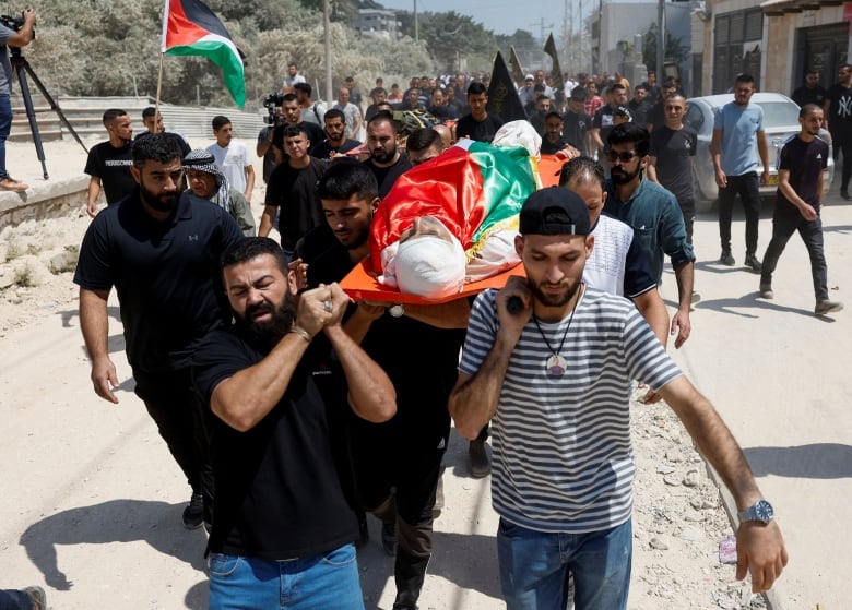  Mourners carry the body of a Palestinian who was killed by Israeli forces, during his funeral in Nur Shams refugee camp, near Tulkarm in the Israeli-occupied West Bank, August 30, 2024. 