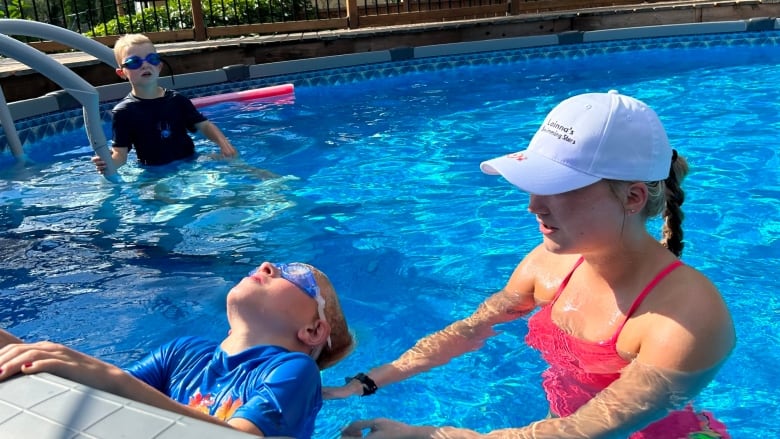 a girl helps a boy swim in a pool