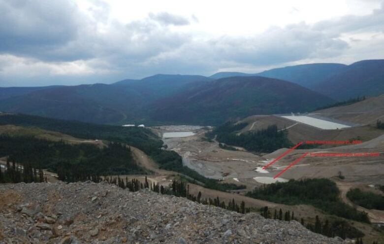 A view of mountains and a mine site, with red arrows drawn on the image.