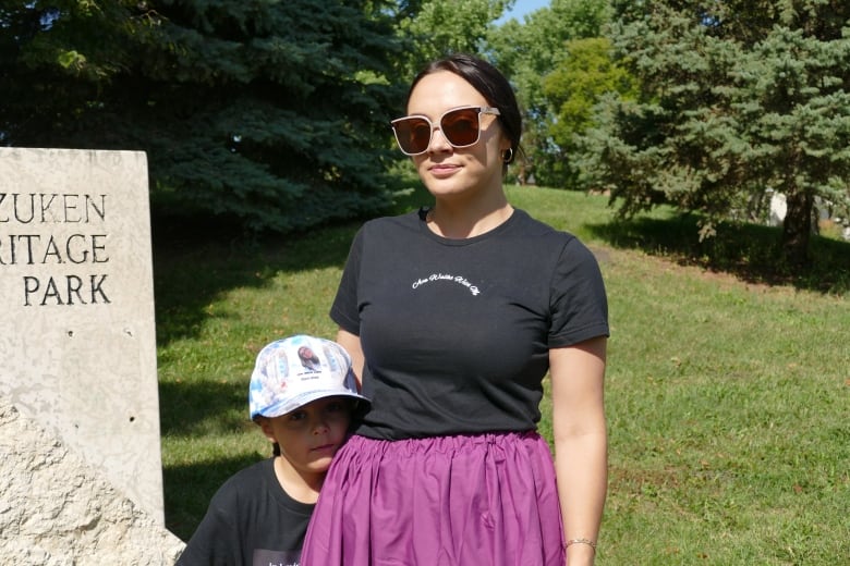 A woman on a black shirt and sunglasses and a child outdoors