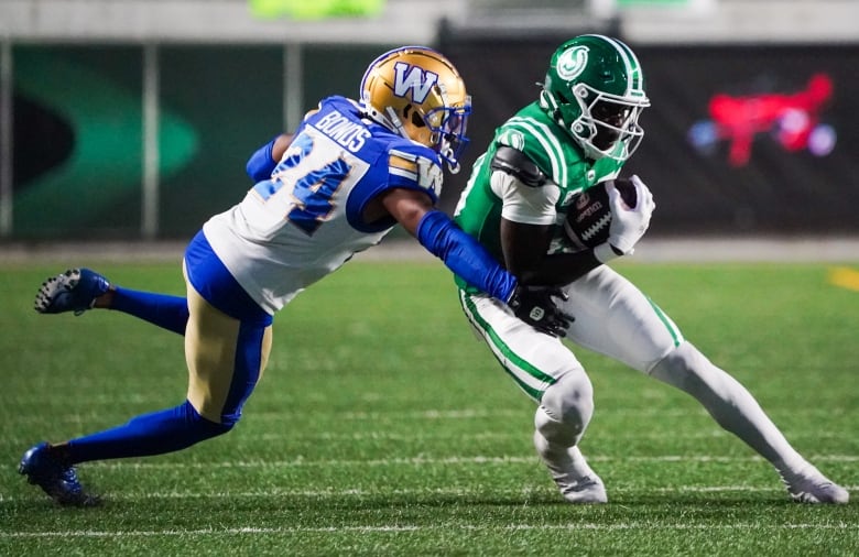 One football player lunges towards another who has the ball