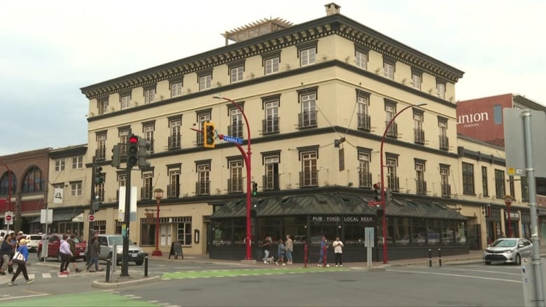 A hotel pictured as people cross the road in a city street