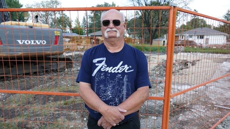 A man stands in front of a fence 