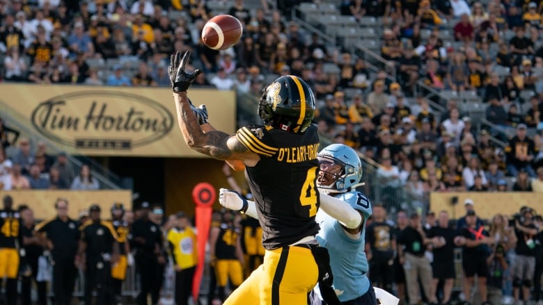 Hamilton Tiger Cats wide receiver Brendan O'Leary-Orange (4) makes a catch while defended by Toronto Argonauts defensive back DaShaun Amos (8) during CFL football game action in Hamilton, Ont., Monday, Sept. 2, 2024. 