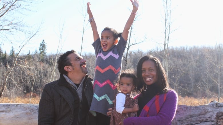 Four members of a family pose for a picture in a park.