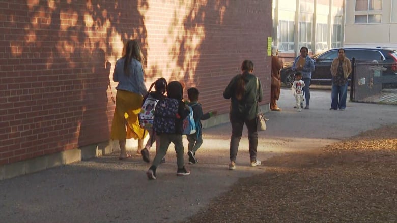 Students walking outside of school with an adult.