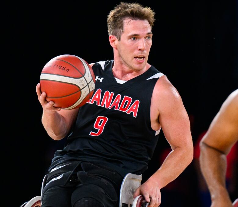 A man holding a basketball while mid-play in wheelchair basketball