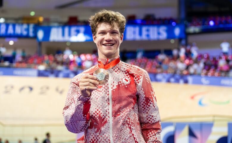 A smiling man holding a medal