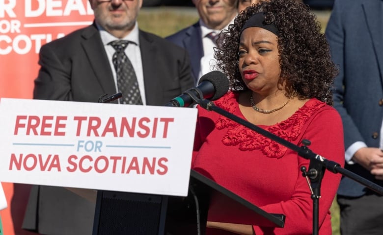 A woman stands at a podium with people behind her.