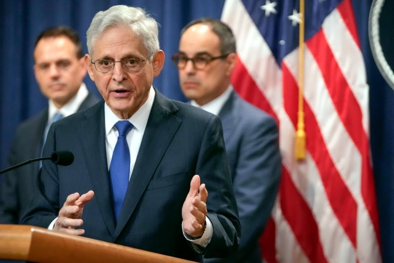 A man in a suit talks to reporters.