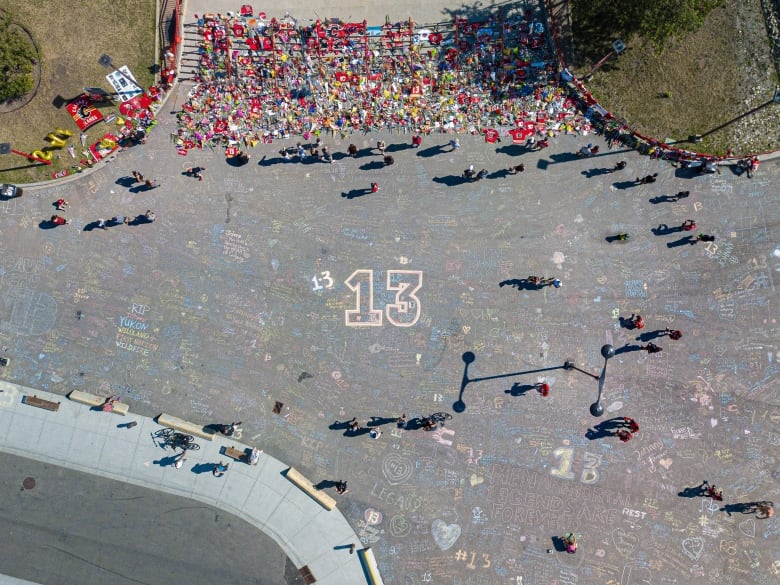 A plethora of red Calgary Flames gear can be seen above a large 13 drawn in chalk on dark grey pavement.