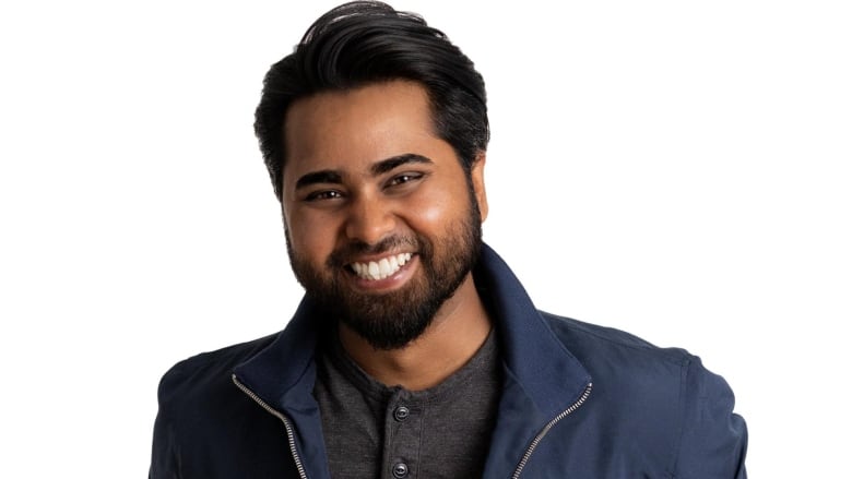 A portrait of a man with dark hair and a beard smiling.