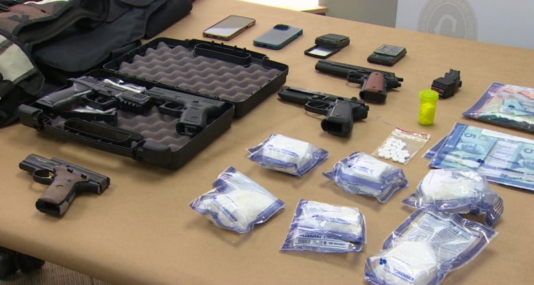 Table with five guns, bags of cocaine, drugs and money. 