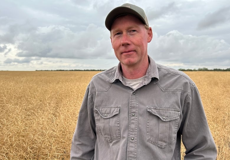 Rob Stone is standing in the middle of a canola field