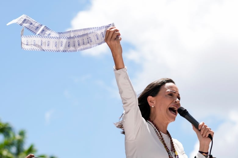 Opposition leader Maria Corina Machado displays vote tally sheets during a protest against the reelection of President Nicols Maduro one month after the disputed presidential vote which she says the opposition won by a landslide, in Caracas, Venezuela, Wednesday, Aug. 28, 2024.