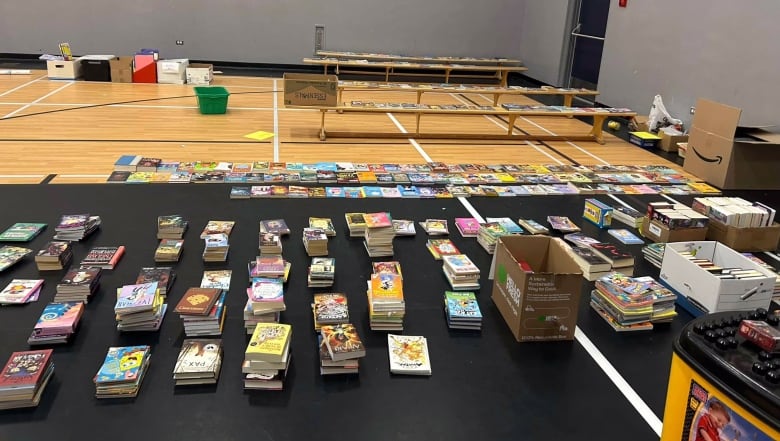 Books are spread out on a mat on a school gymnasium floor.