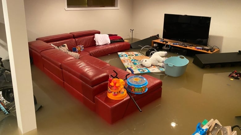 A couch and some household objects in a basement are seen floating in two feet of brown water.