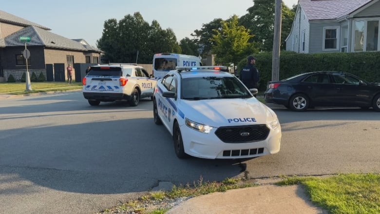 Three police cars parked at a residential intersection.