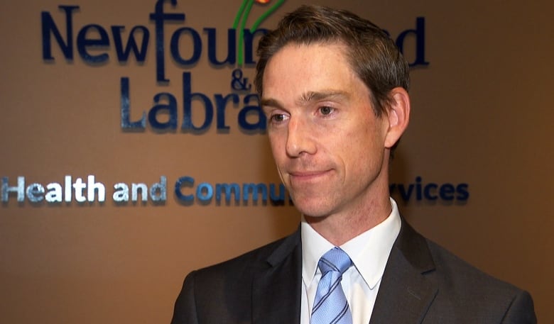 Man in suit in front of wall that says Newfoundland and Labrador.