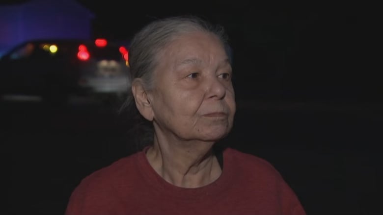 A woman in a red shirt with a neutral expression. 