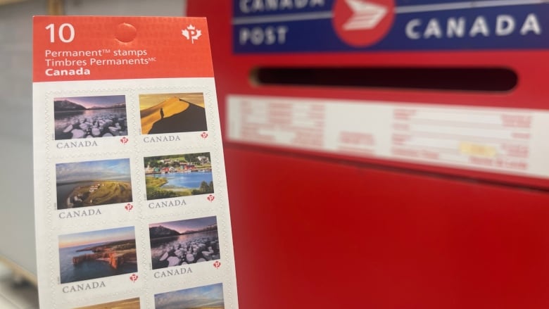 A pack of stamps is in the foreground against the backdrop of a Canada Post mail box.