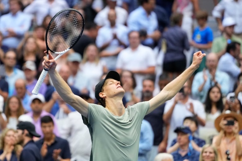 A tennis player lifts his arms in the air.