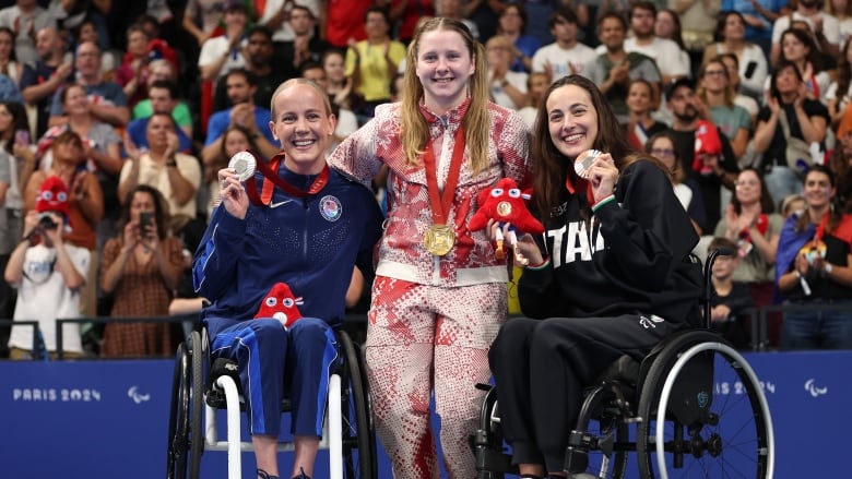 Three athletes pose with medals.