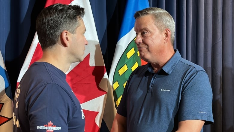 Poilievre shakes hands with middle-aged man in blue polo shirt