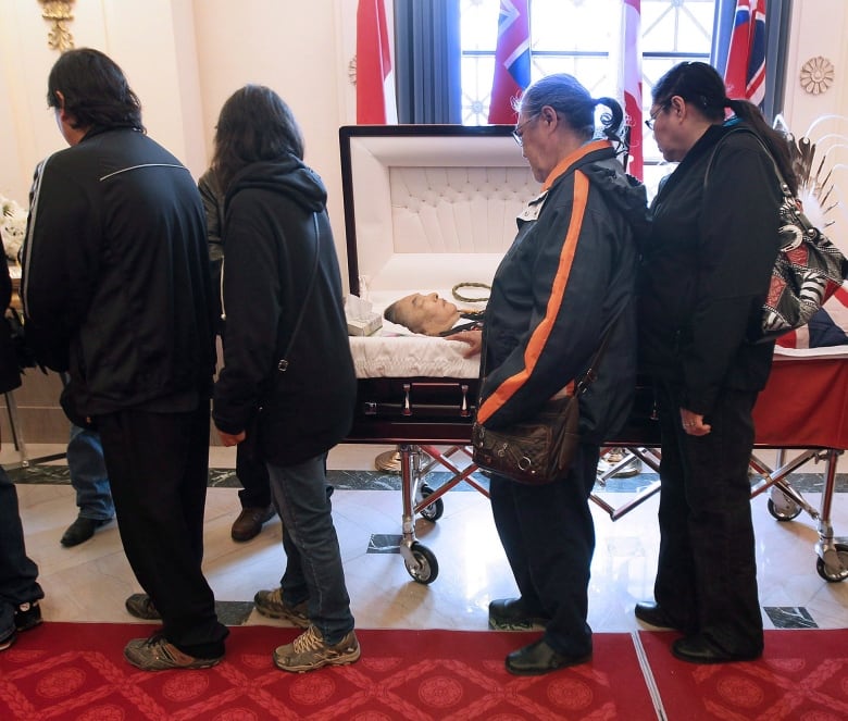 People line up alongside a casket