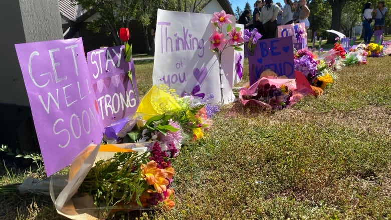 Flowers and posters sit on the grass