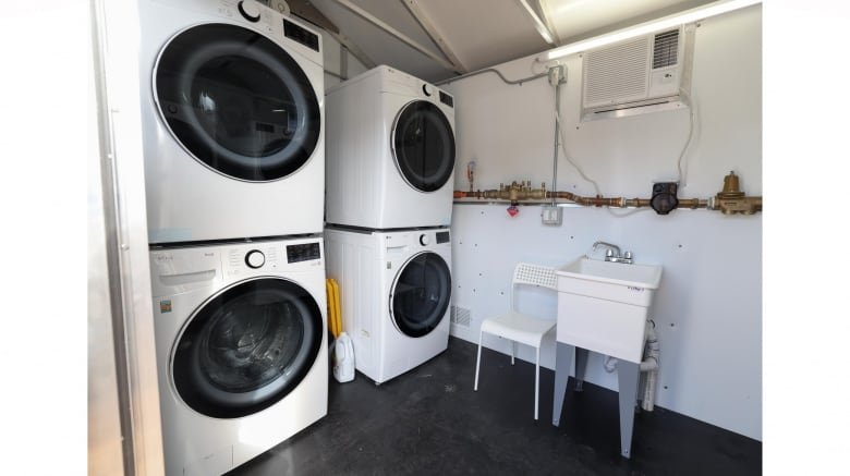 A small laundry room with two sets of washers and dryers. 