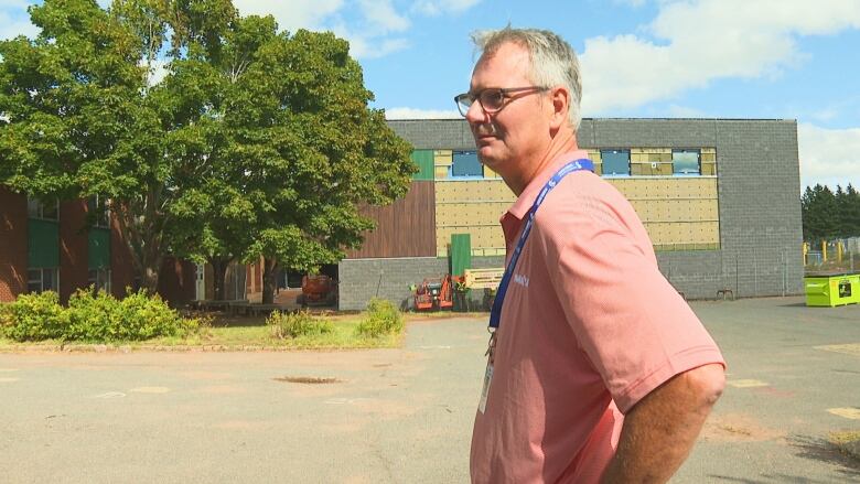 Man with grey hair standing outside school.