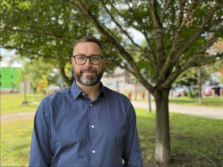 A councillor standing outside in a park near the water. 