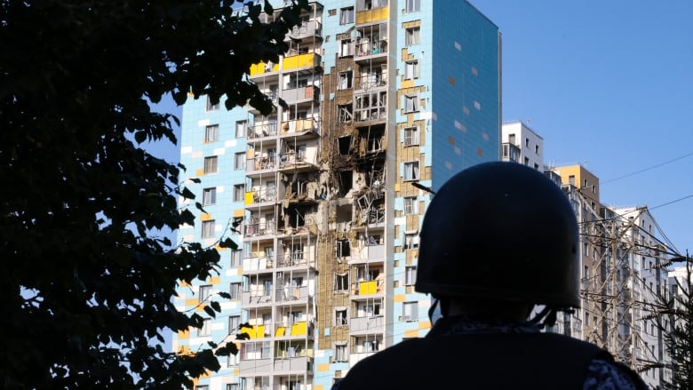 Several heavily damaged units and balconies of a high-rise apartment building are shown in closeup.