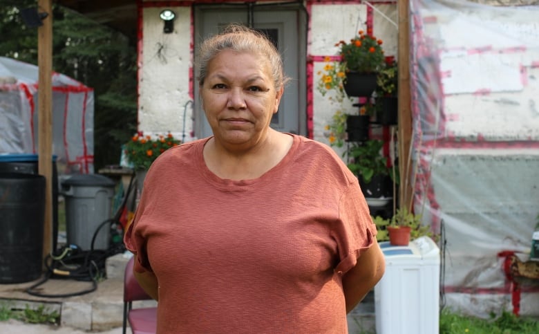 A woman in a salmon-coloured t-shirt is pictured in front of a trailer in Conklin, Alta.