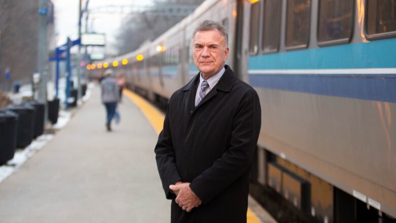 A man poses for a photo in front of a train. 