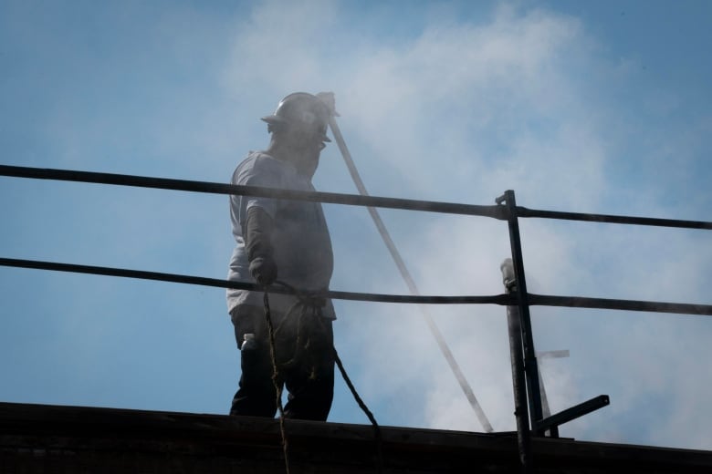 A man stands on a roof among smoke.