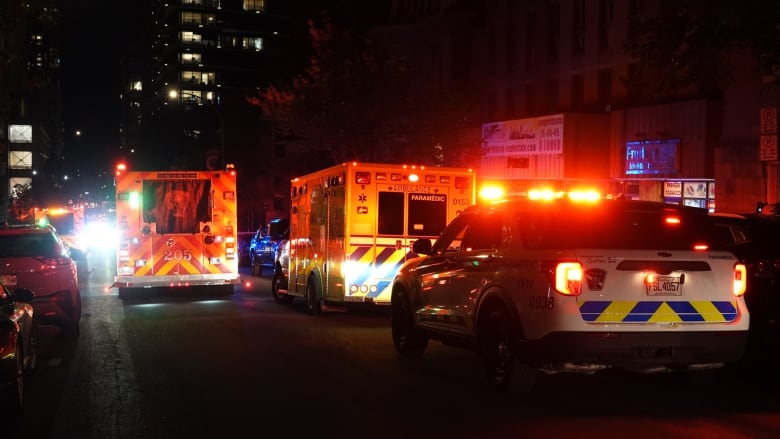 Several emergency vehicles on a street at night. 