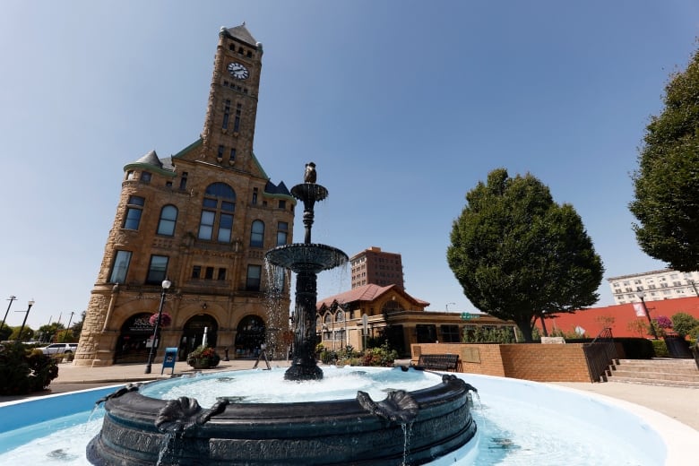 A fountain and an older, august-looking building with a clock tower are shown.