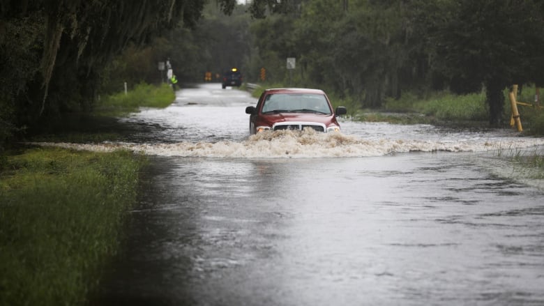 A truck tries to drive through a flooded road.