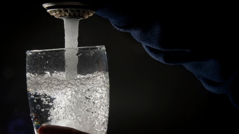 Drinking water is poured into a glass from a faucet 