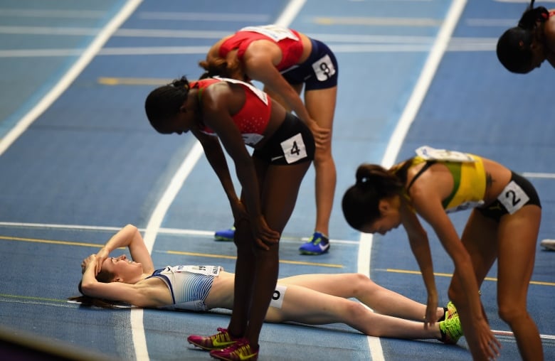 A female athlete lays exhausted on the track of a 1500 m race.