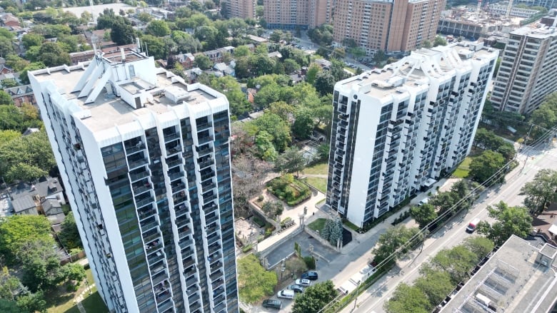 Drone shot of two apartment buildings with tree-lined residential streets behind them. 