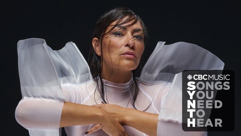 Elisapie (an Inuk woman) poses in front of a black background. She wears a sheer white top, with fabric jutting out at the shoulders. The CBC Logo and the words 