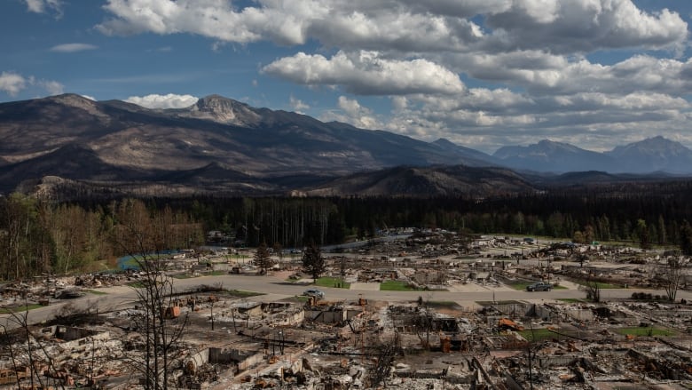 A view of a mountainous landscape. The wildfire-damaged townsite of Jasper is visible below.