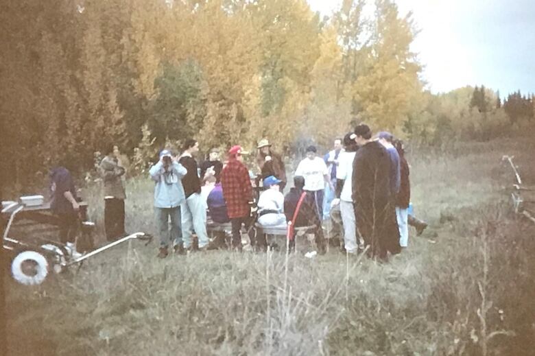 An old grainy photo of people standing outdoors at a camp. 